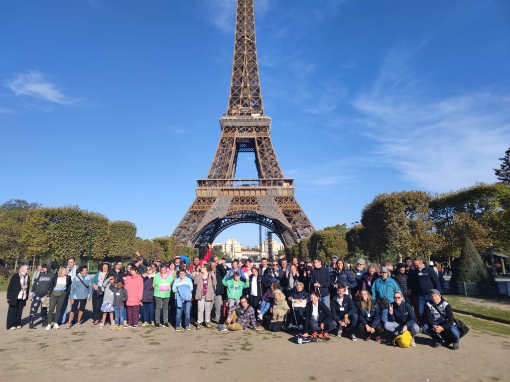 Un grand groupe pose devant la tour Eiffel.