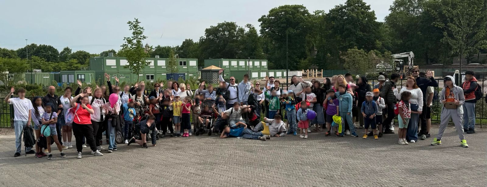 Un groupe d’enfants et d’adultes pose à l’extérieur.