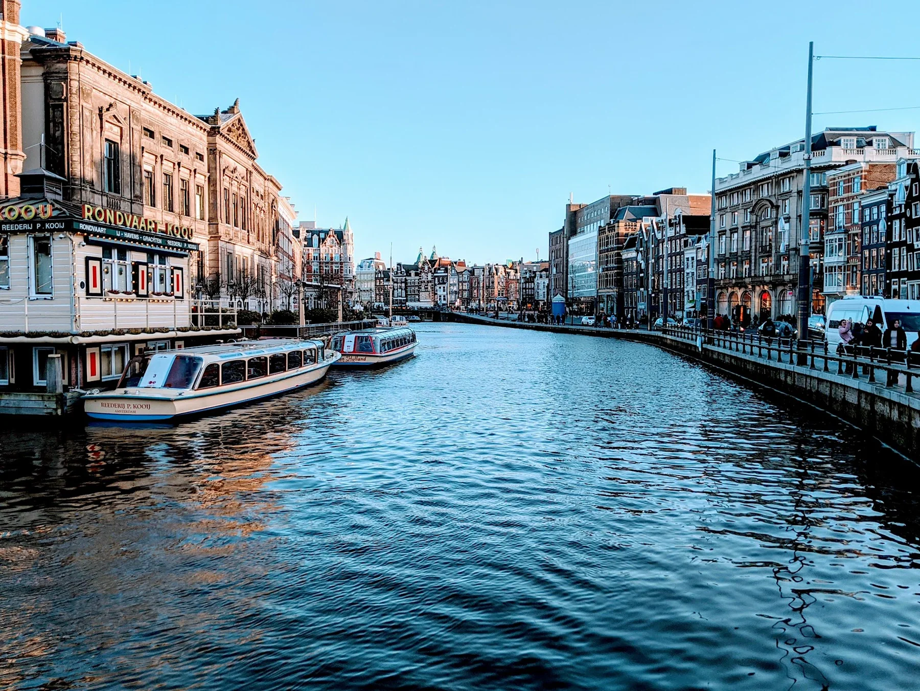 Canal bordé de bâtiments anciens et de bateaux à Amsterdam.